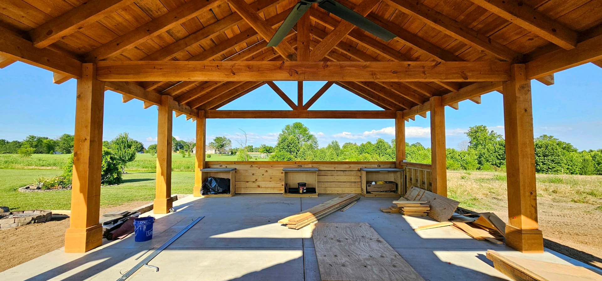 Inside a timber frame pavilion looking out over a field