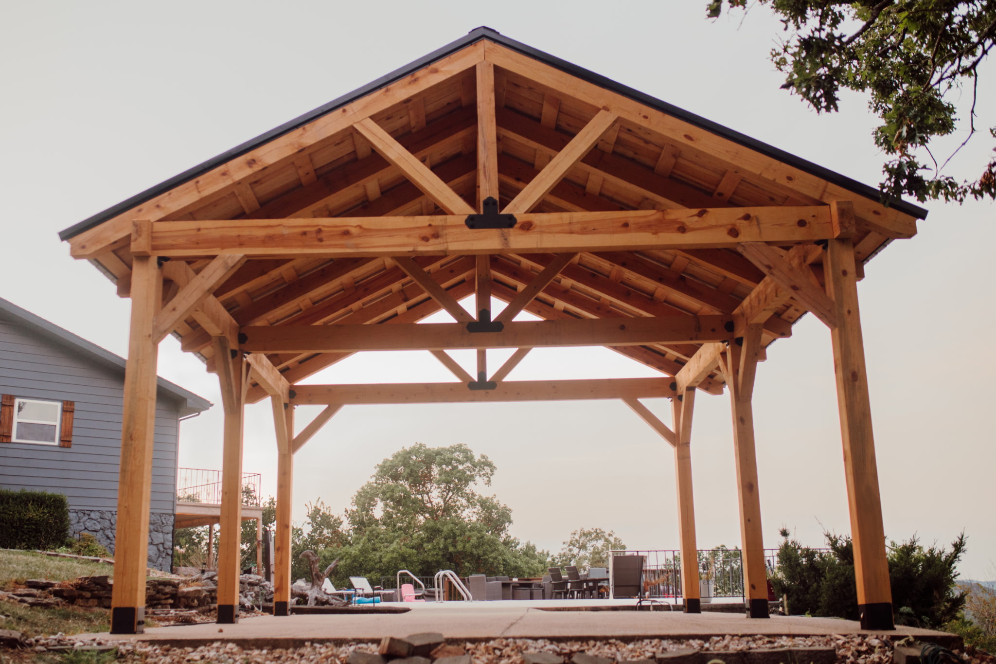 Large timber pavilion kit installed beside a pool